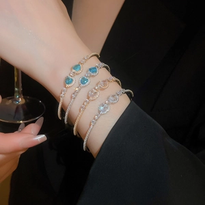 Close-up of luxury gold bracelets with blue and white heart-shaped zircon stones