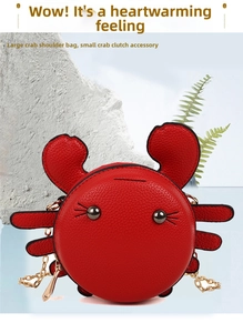 Close-up of a small red crab shaped leather crossbody bag with a gold chain strap