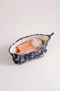 Detailed embroidery texture on dark blue quilted makeup bag with gold floral patterns