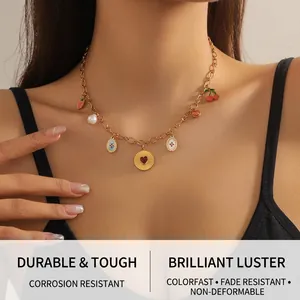 Détail du collier doré avec charms cerise, fraise et perles porté sur le cou de femme