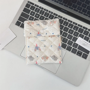 Close-up of quilted ivory elephant pouch with snap closure on a laptop keyboard