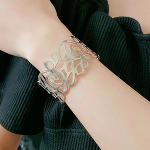 Detailed view of silver open cuff bracelet with intricate hollow rose flower pattern