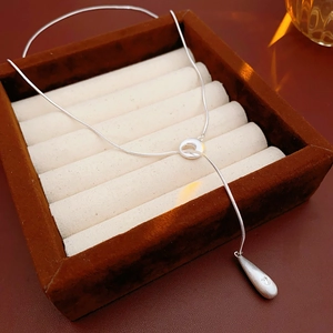 Detail of silver Y-shaped drop pendant necklace on brown velvet jewelry tray