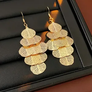 Elegant gold layered dangle earrings with textured hollow mesh leaf design on black display