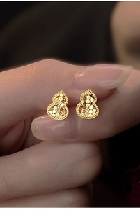 Close-up of 18k gold plated gourd earrings with a textured shimmering surface detail