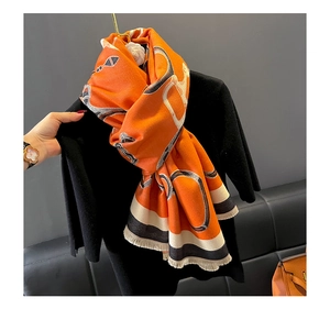 Detail of orange cashmere-like scarf with equestrian bridle print and fringe edges