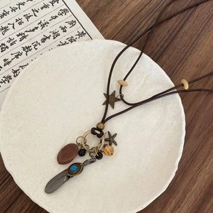 Detail of vintage bohemian necklace featuring metal feathers and round wooden pendant charms