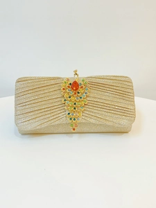 Detailed view of golden pleated evening clutch featuring a colorful peacock jewel clasp