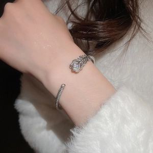 Detail of silver feather bangle with pavé zircons worn on a soft white background