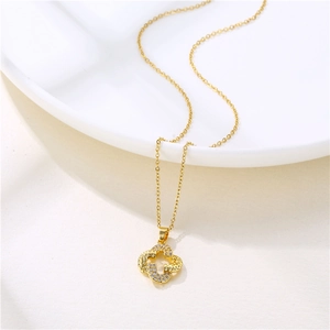 Gold stainless steel clover necklace with pavé zircons on a white ceramic plate