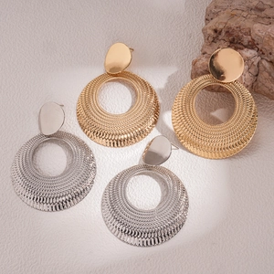 Detail view of gold and silver hammered round earrings on natural stone background