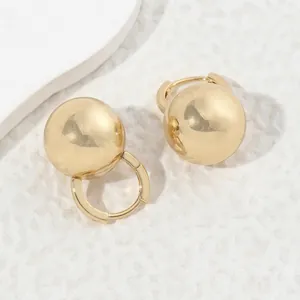 Minimalist golden spherical hoop earrings with a polished mirror finish on white stone