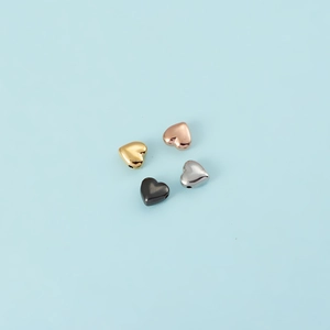 Detailed view of polished heart charms in gold, rose gold, silver and black finishes