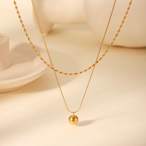 Close-up of double-layer gold stainless steel necklace with beads and spherical pendant
