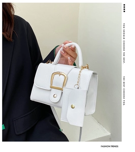Detail of white litchi leather handbag with gold buckle and mini charm pendant