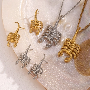 Detailed macro view of gold and silver scorpion pendant necklaces and stud earrings
