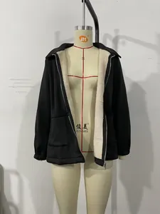 Detail of a black zip-up jacket with soft white faux fur lining and ribbed cuffs