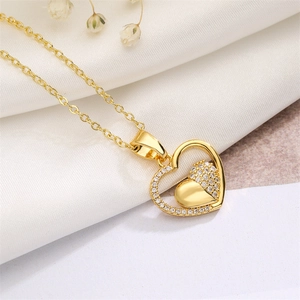 Macro shot of gold heart pendant with zircon stones on white fabric background