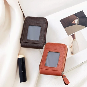 Detailed view of pebbled leather zipper wallets in brown and orange on white fabric