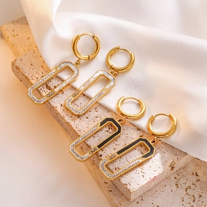 Macro detail of geometric zircon earrings with gold finish on a beige stone