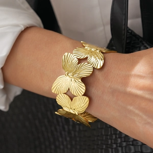 Detail of wide gold butterfly cuff bracelet with intricate engraved wing patterns