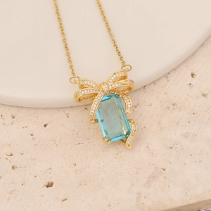 Golden necklace with blue rectangular gemstone pendant and sparkling butterfly detail