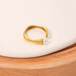 Irregular golden stainless steel open ring with a white pearl on a stone display