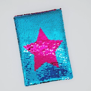 Dettaglio delle paillettes reversibili su un taccuino blu con motivo a stella rosa