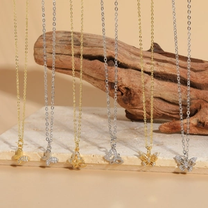 Elegant gold and silver butterfly pendant necklaces with zircon inlay on marble base