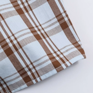 Macro shot of brown and blue plaid poplin fabric with detailed stitched hem edges