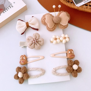 Dettaglio di 8 fermagli per capelli in peluche beige con motivi di conigli e fiori