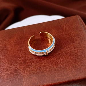 Macro shot of 18k gold plated open ring with blue enamel flower and cubic zirconia