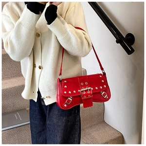 Détail du sac baguette rouge style punk avec clous argentés et boucles sur la bandoulière