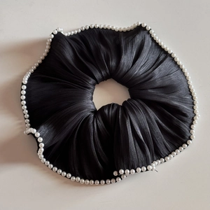 Close-up of black silk scrunchie with delicate white pearl trim on white background