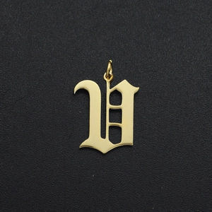 Macro shot of a golden gothic letter U charm with polished finish and circular bail