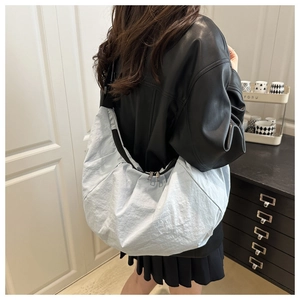 Detailed side view of a large light blue pleated dumpling bag worn by a model