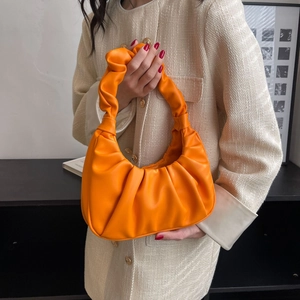 French style orange pleated cloud bag worn as a shoulder bag by a chic model