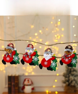 Close-up of fabric Christmas ornaments with Santa and reindeer on rustic wooden branches