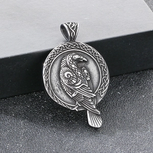Detail of vintage stainless steel round pendant with Nordic wolf and raven engraving