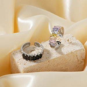 Close-up of adjustable silver rings with black and colorful gems on golden silk
