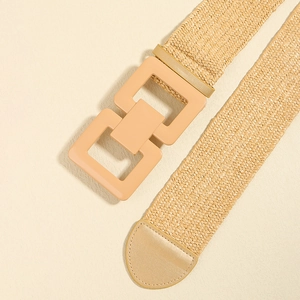Close-up of beige woven waist belt with geometric square buckle and leather tip detail