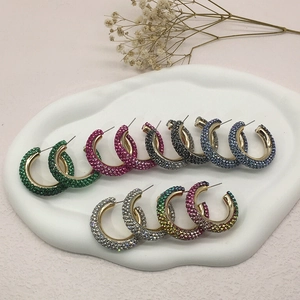 Colorful C-shaped rhinestone hoop earrings in multiple shades on a ceramic tray