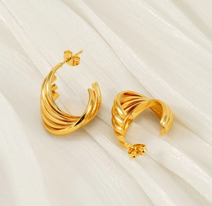 Detail of 18K gold-plated irregular spiral hoop earrings on elegant white satin fabric
