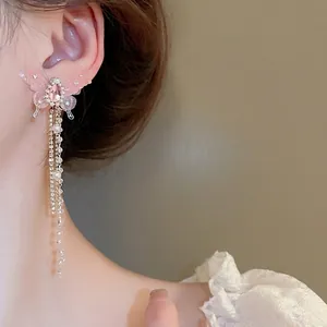 Elegant butterfly drop earrings with pink crystal and long sparkling tassel on model