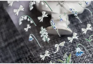 Détails macro d'autocollants 3D pour ongles aux motifs de muguet et de rubans