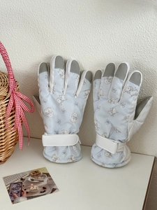 Detail of light blue winter gloves featuring cute rabbit patterns and adjustable wrist strap