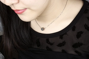 Detail of S925 silver necklace with grey moonstone pendant on female model neck