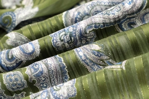 Macro detail of olive green paisley fabric with vertical metallic gold stripes