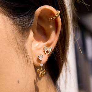 Macro shot of gold bow heart earrings and cubic zirconia butterfly stud earrings set