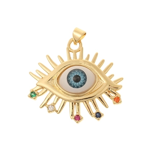 Close-up of golden evil eye pendant featuring a blue iris and multi-color crystal rays